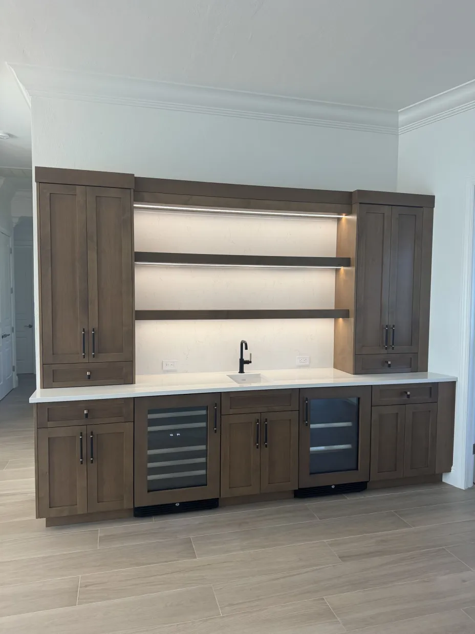 Custom dry bar with full-height cabinetry, open lit shelving, sink, and beverage coolers