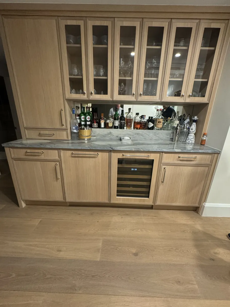 White oak dry bar cabinetry with marble counter and wine fridge