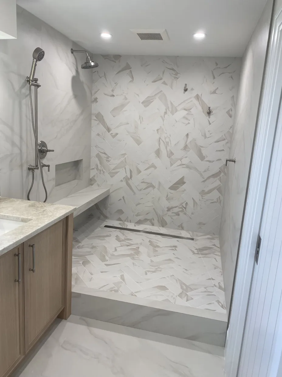 Spa walk-in shower with marble herringbone tile and floating bench